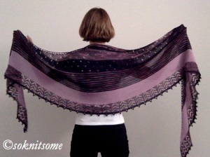 rear view of woman holding out large black and purple shawl